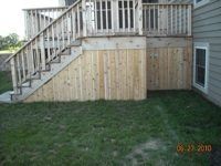 A wooden deck with stairs leading up to it and a wooden fence surrounding it.