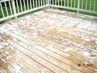A wooden deck with peeling paint and a white railing.