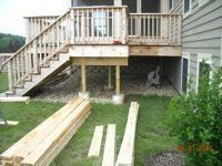 A wooden deck is being built in the backyard of a house.