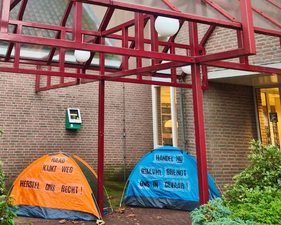 Twee tenten staan ​​voor een bakstenen gebouw.