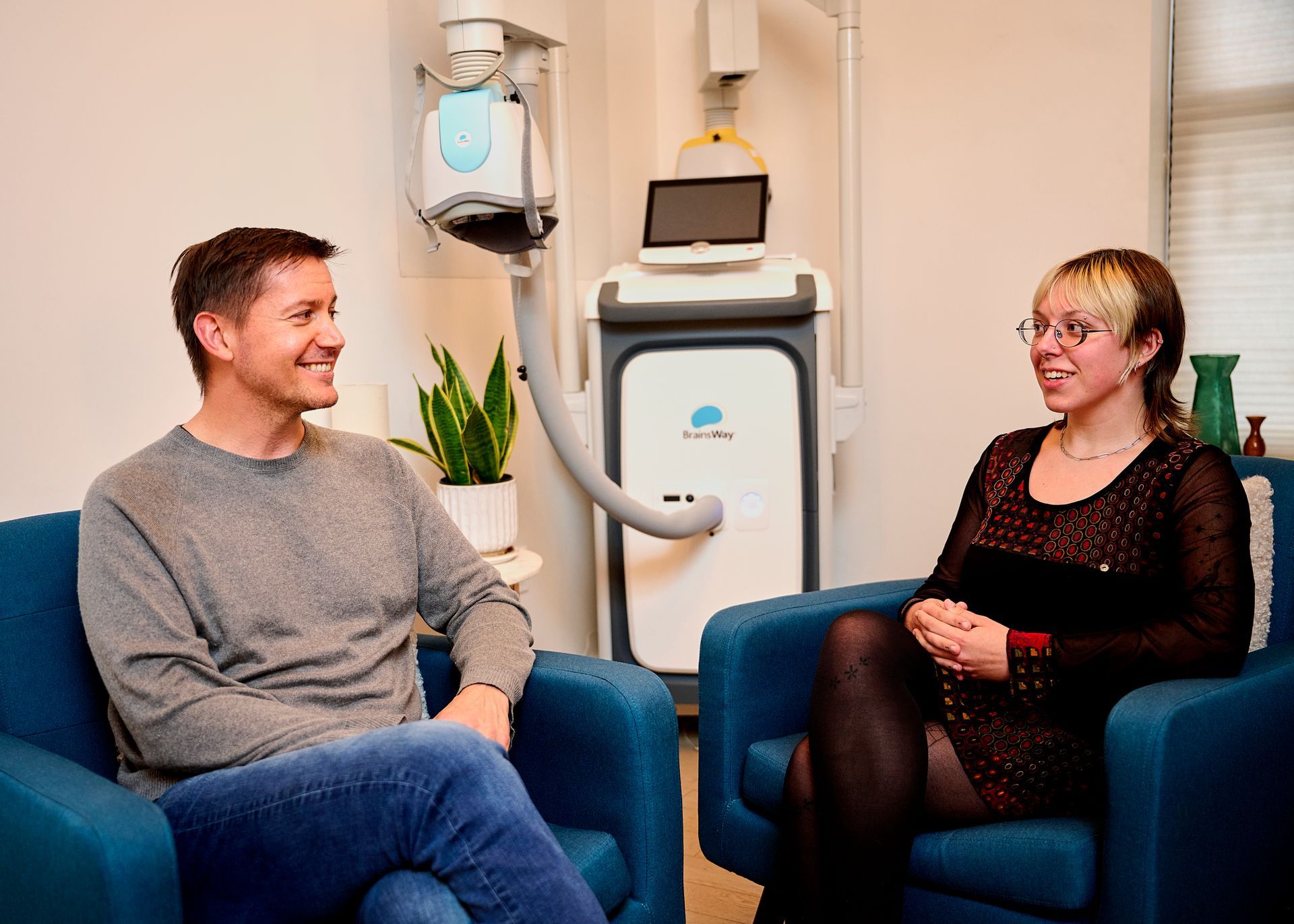 A man and a woman are sitting in chairs in front of a machine.