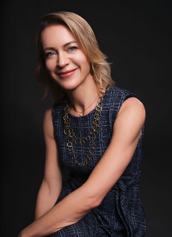 A woman in a blue dress is smiling for the camera