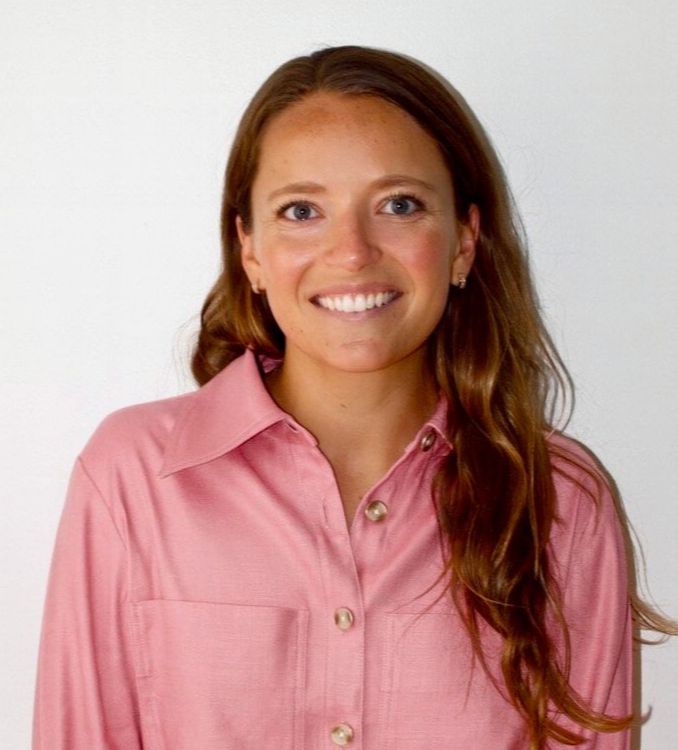 Molly in a pink shirt smiling at the camera, light background.
