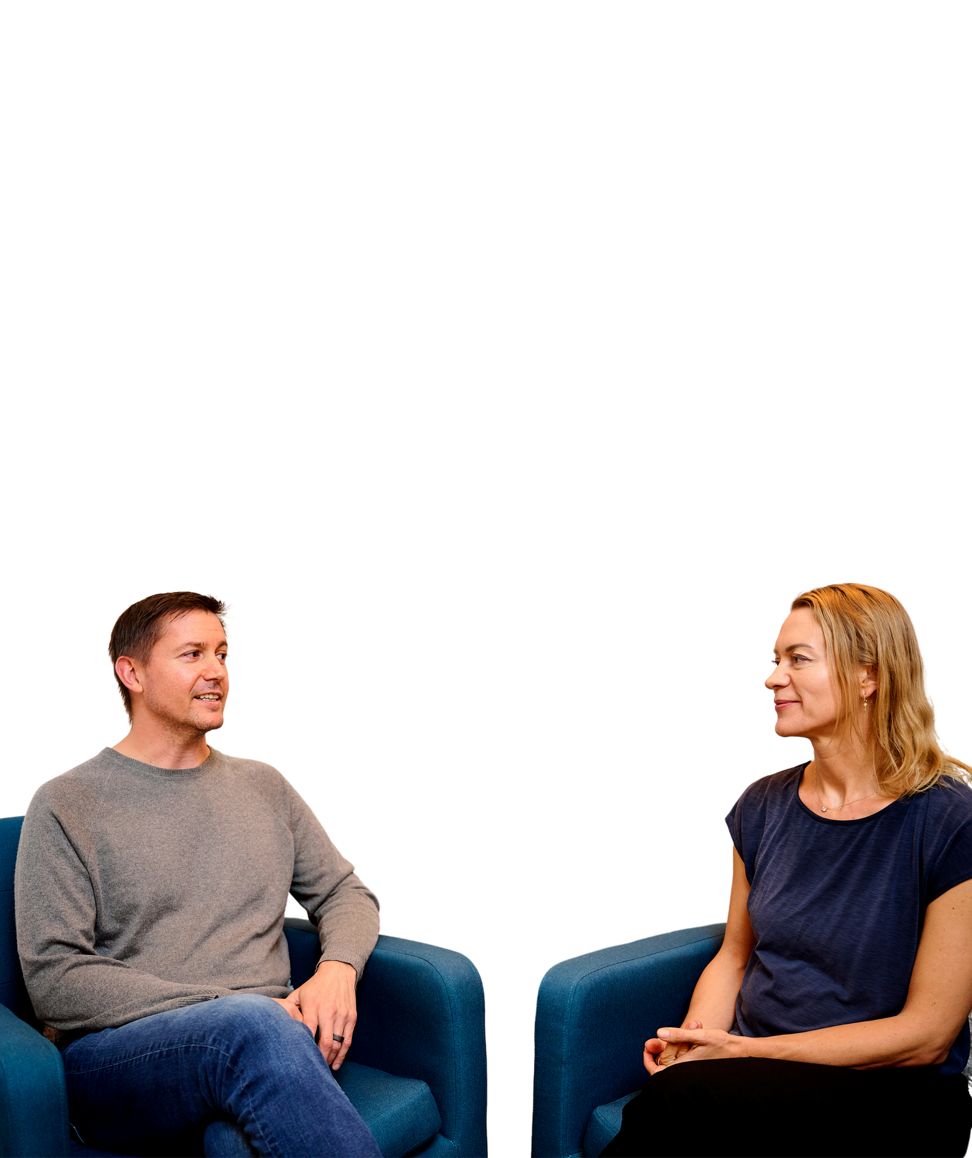 A man and a woman are sitting in chairs talking to each other.
