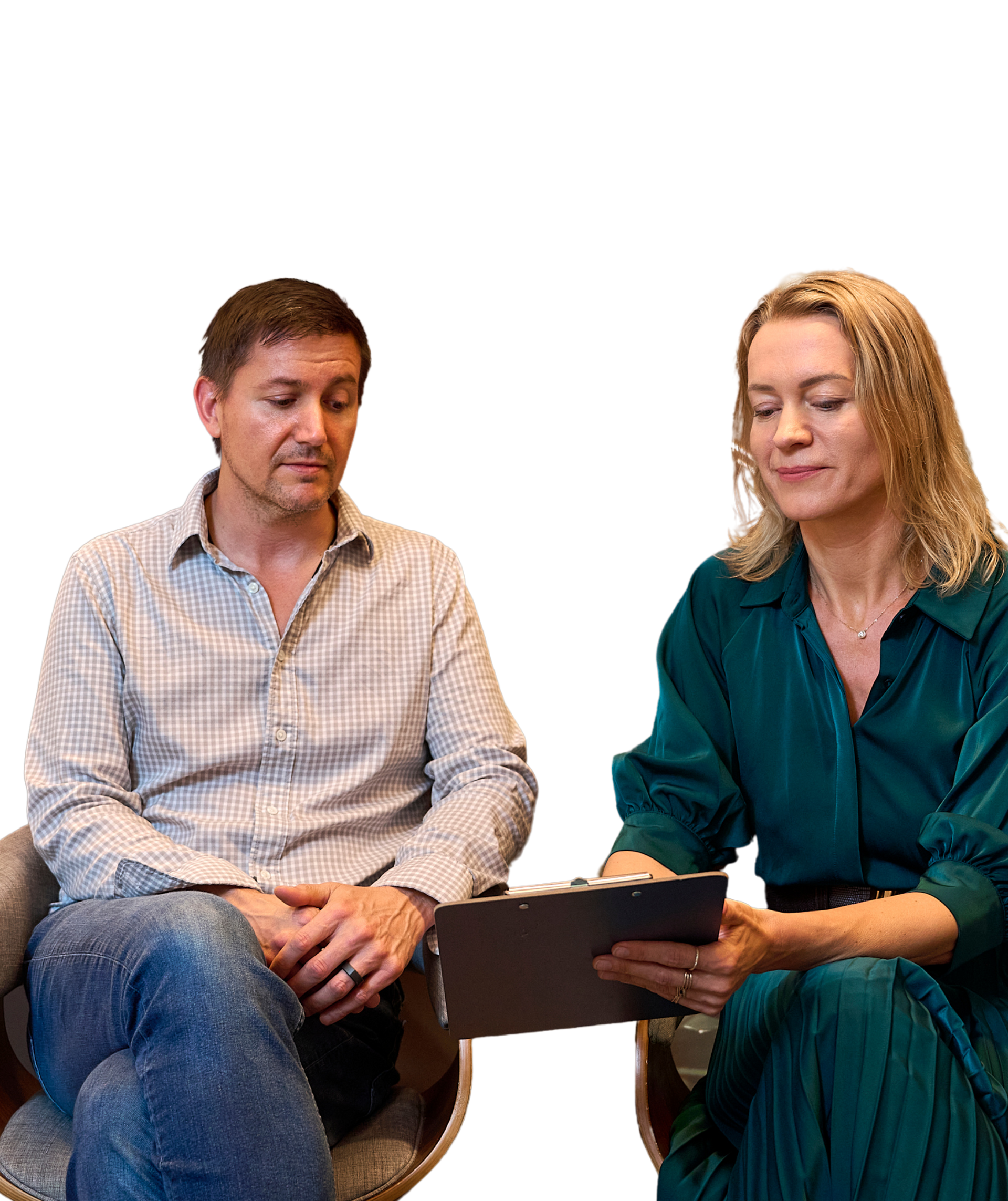 A man and a woman are sitting in chairs looking at a clipboard.