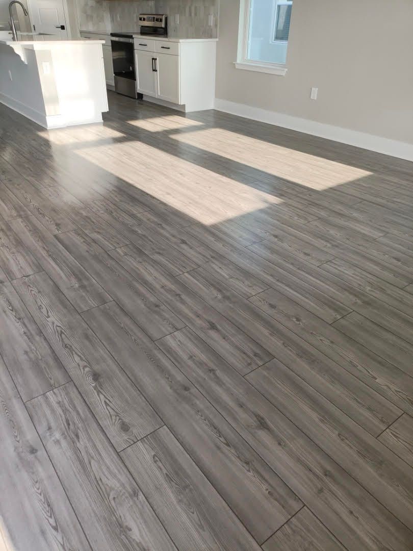 Grey wood-look flooring in a room with natural light and a white kitchen island.