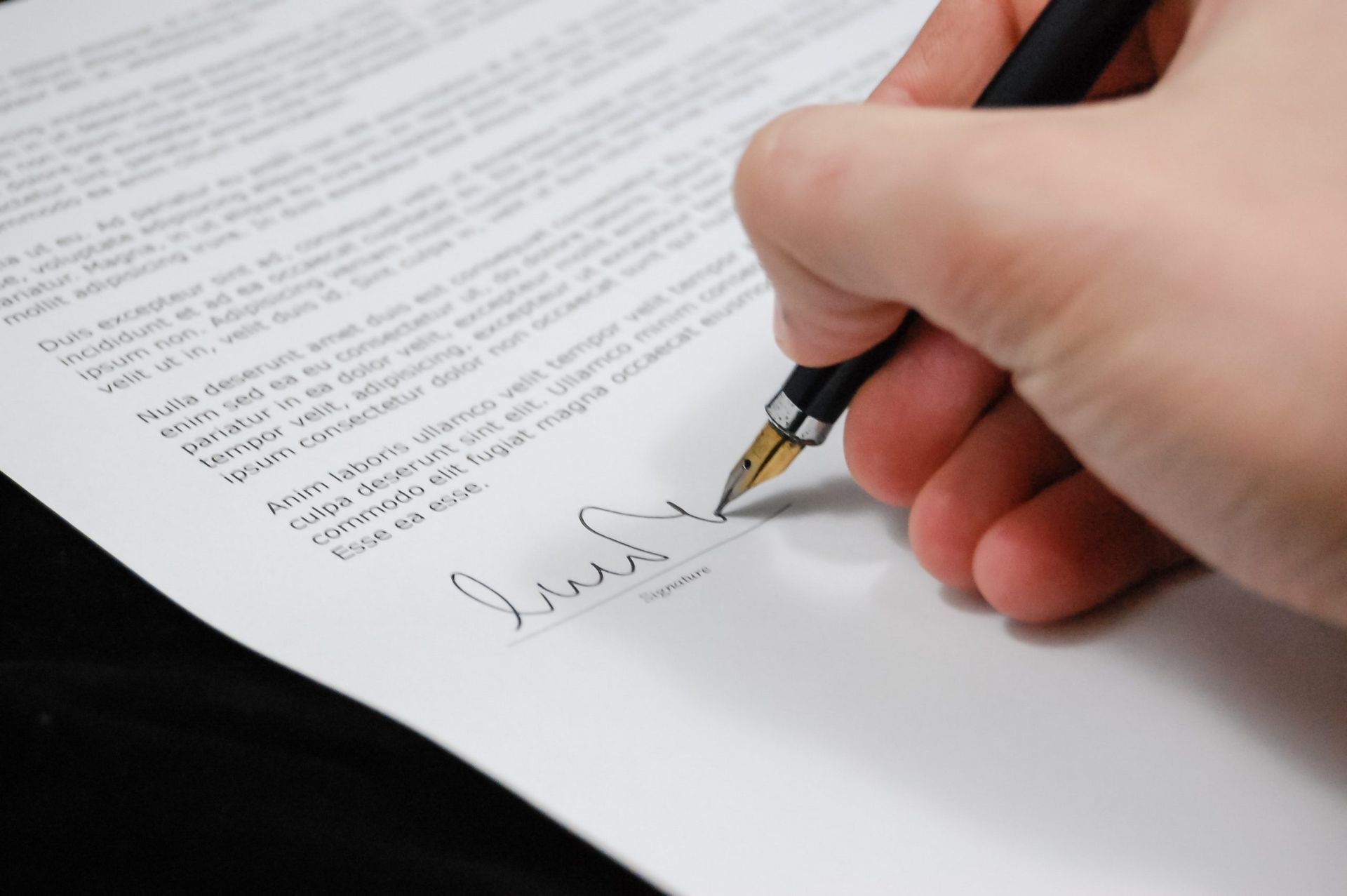 A Gold tipped fountain pen is signing what looks to be an important legal document.