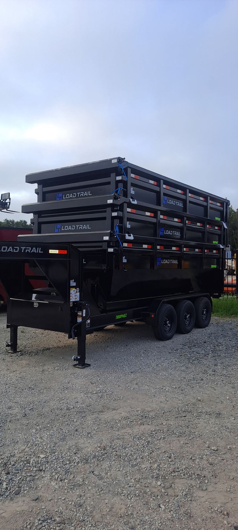 A dump trailer is parked in a gravel lot.