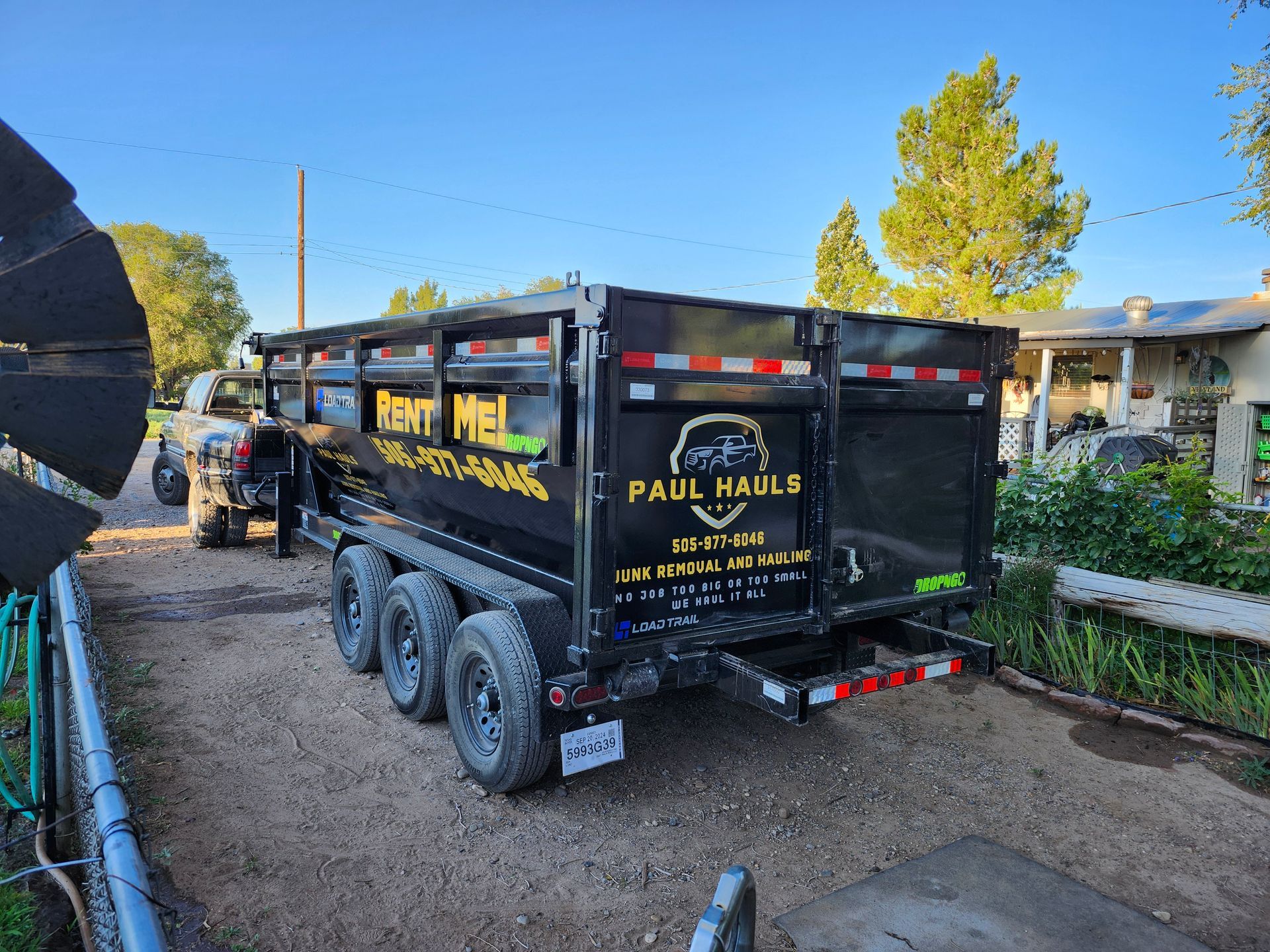 A dump truck is parked in a dirt lot next to a house.
