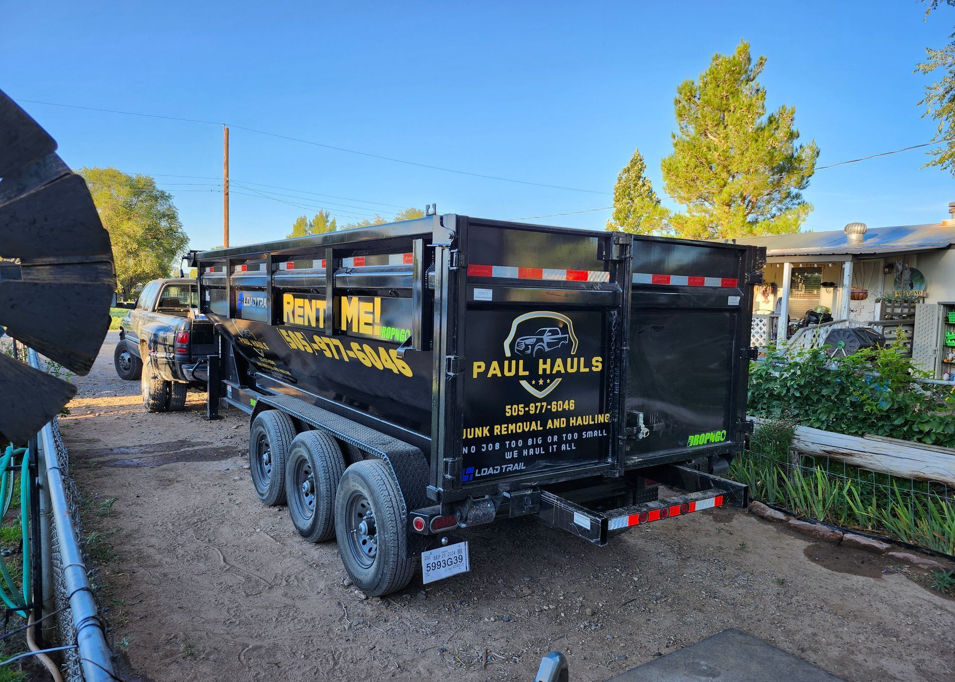 A dumpster trailer is parked in a driveway next to a house.