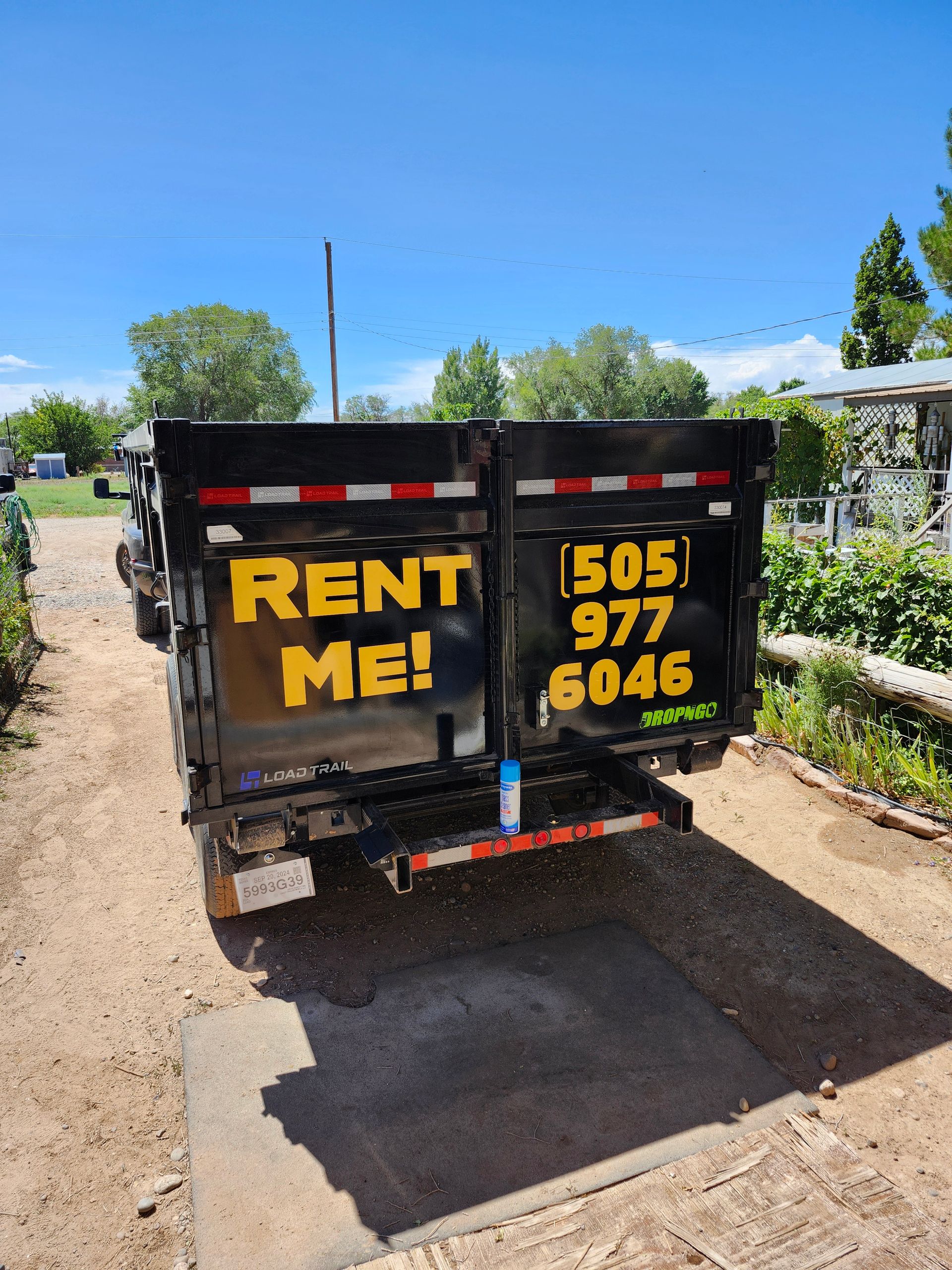 A dumpster that says rent me is parked on the side of the road.