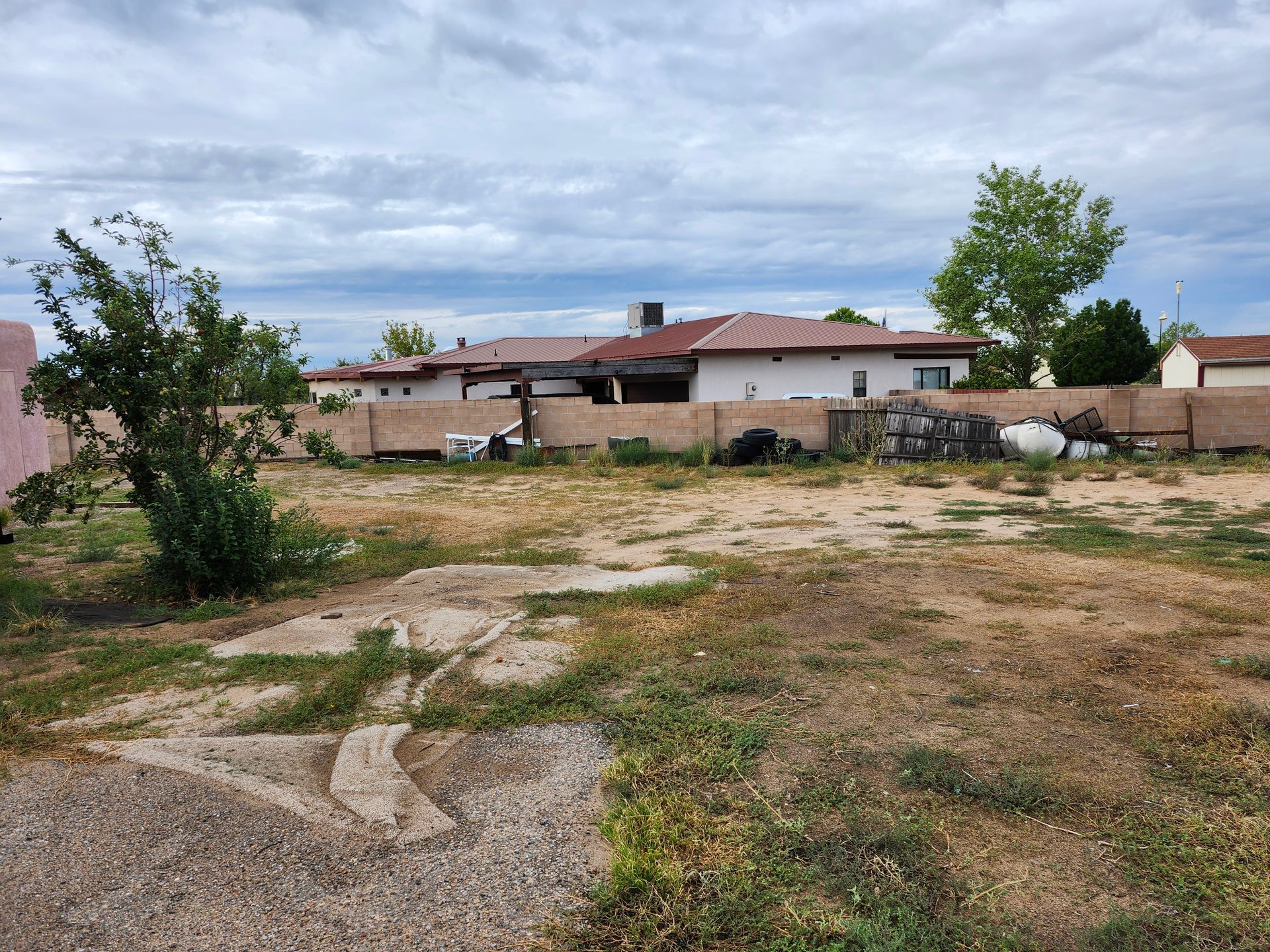 An empty lot with a house in the background.