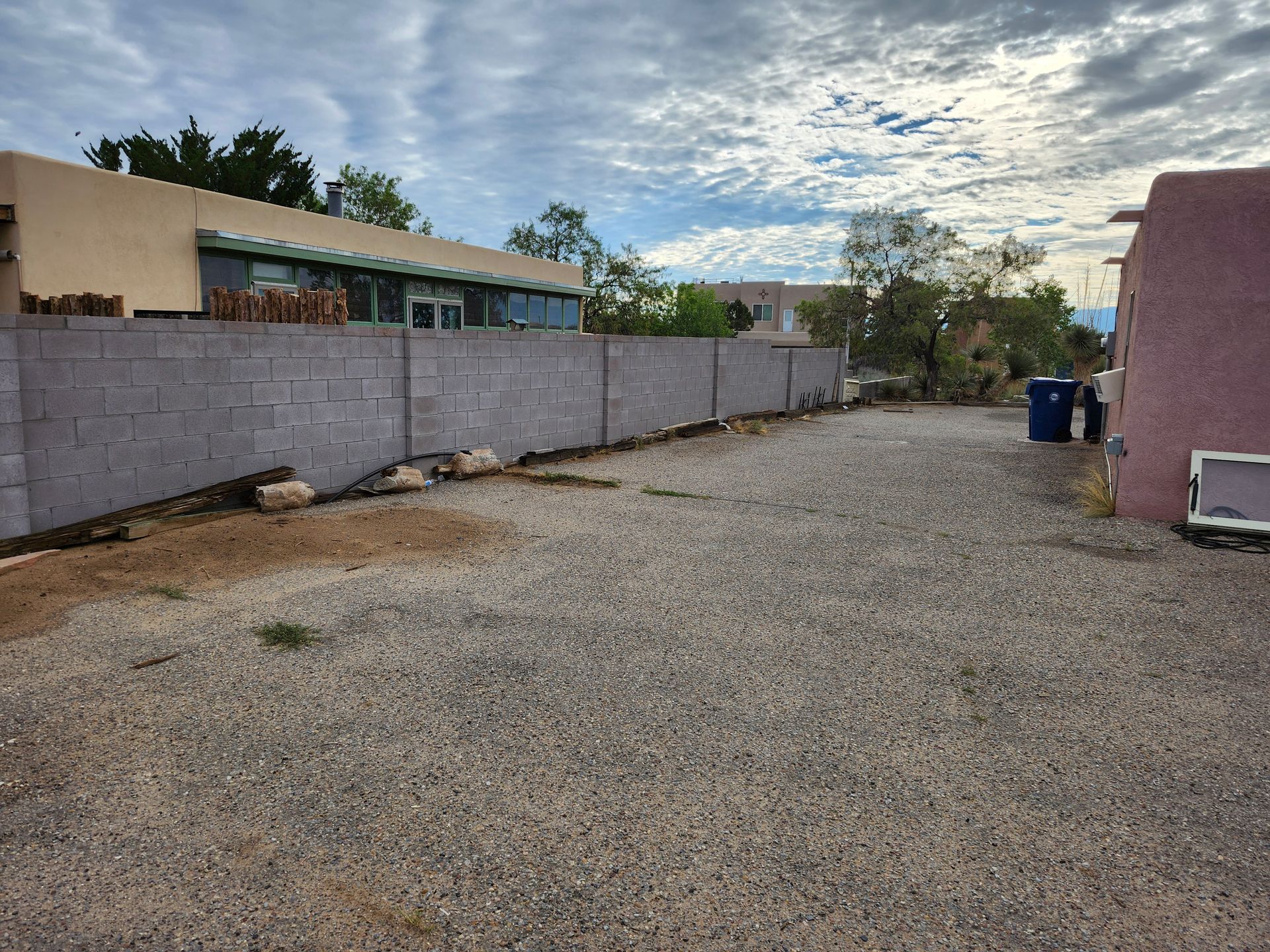 A gravel driveway with a brick wall in the background
