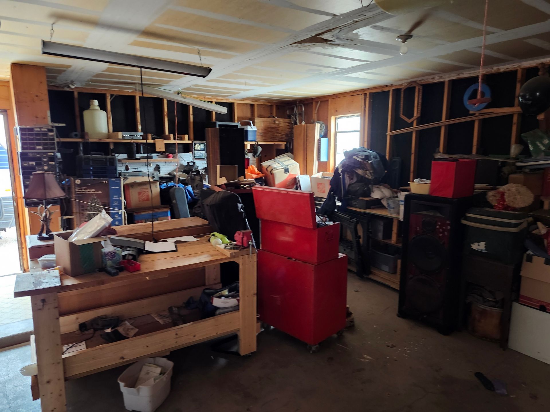 A messy garage with a red toolbox and a wooden workbench.