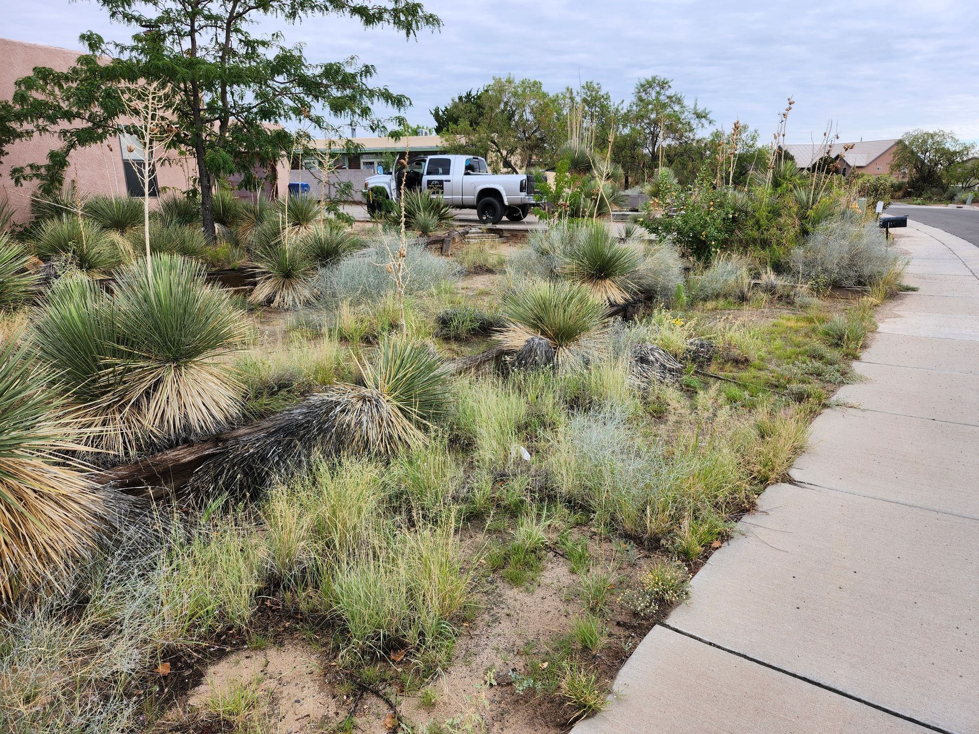 A white truck is parked on the side of the road next to a sidewalk.