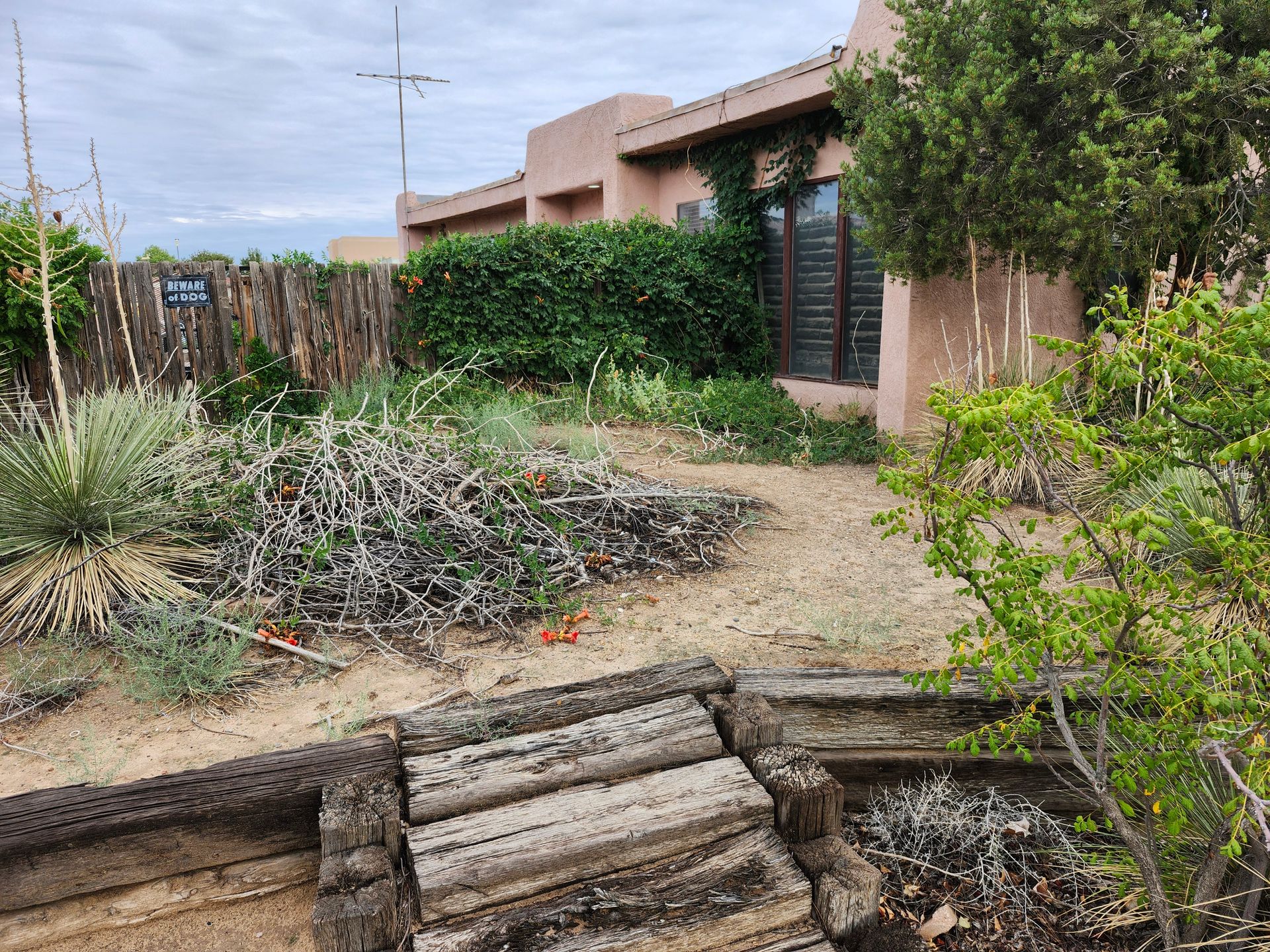 A house with a wooden fence and a wooden bridge in front of it.