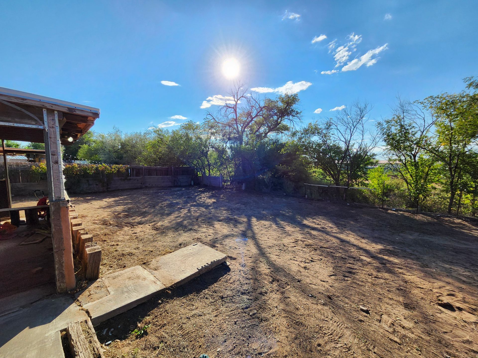 The sun is shining through the clouds over a dirt field.