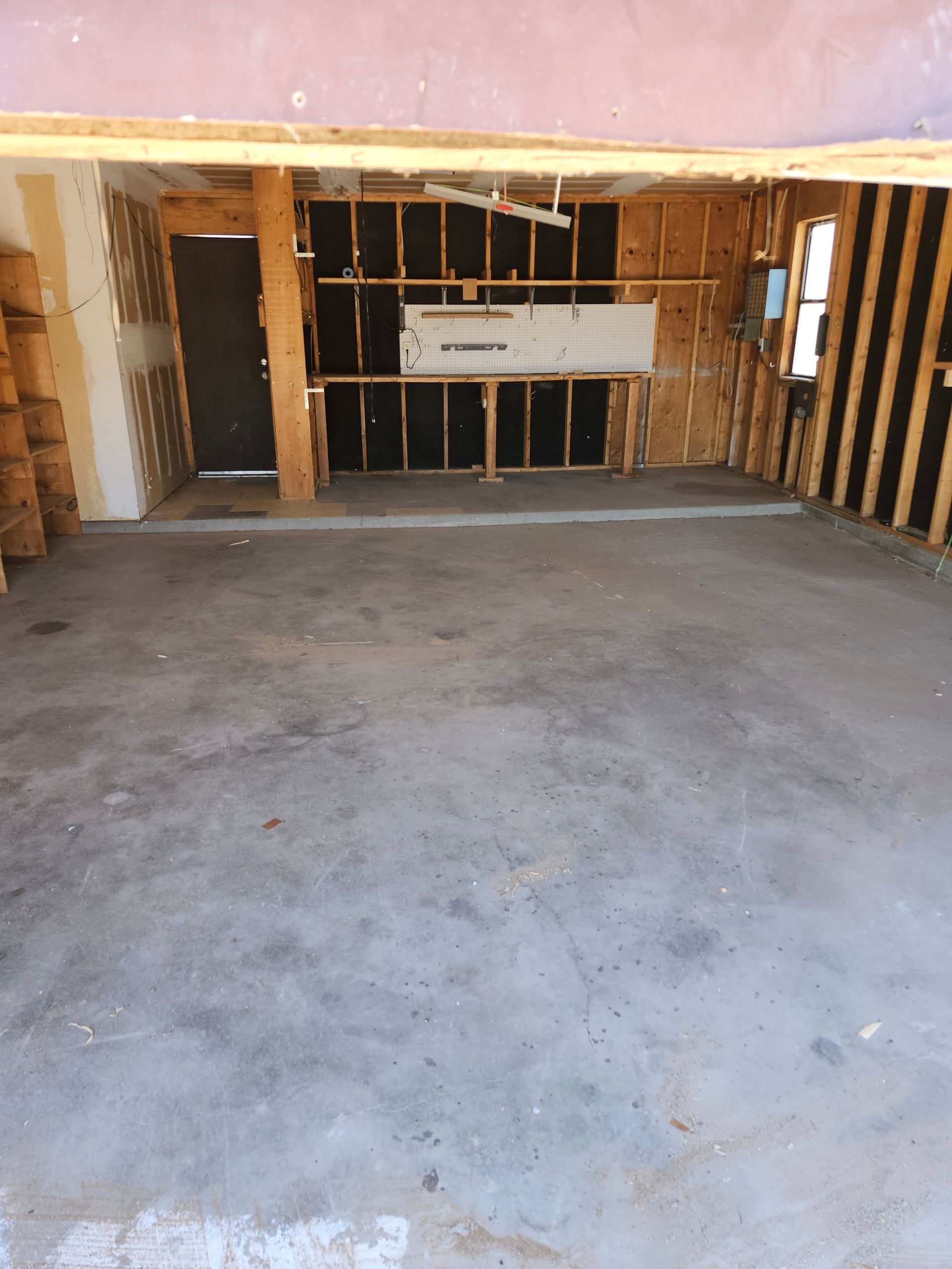 An empty garage with a concrete floor and wooden walls