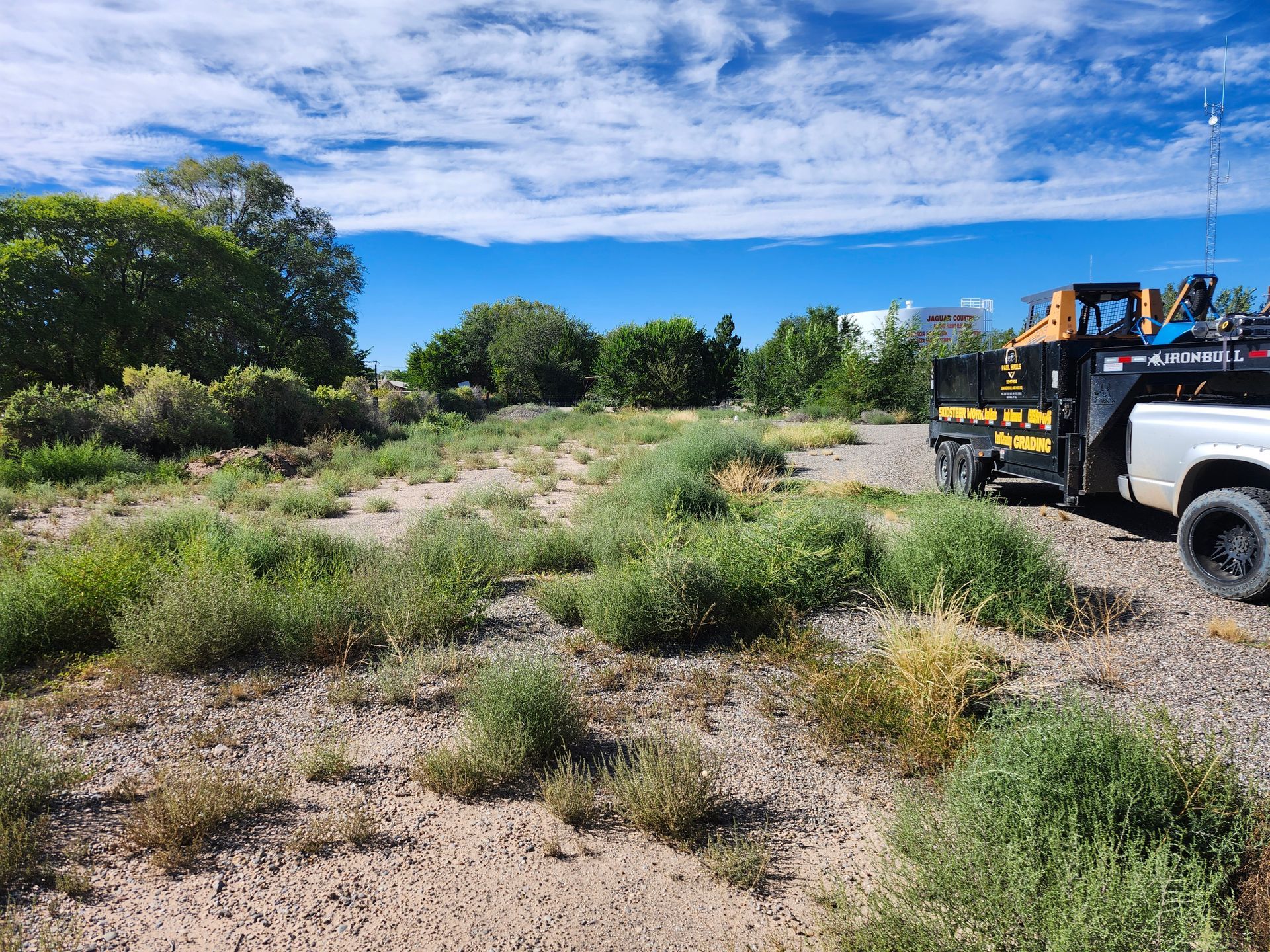 A white truck is parked in the middle of a dirt field.