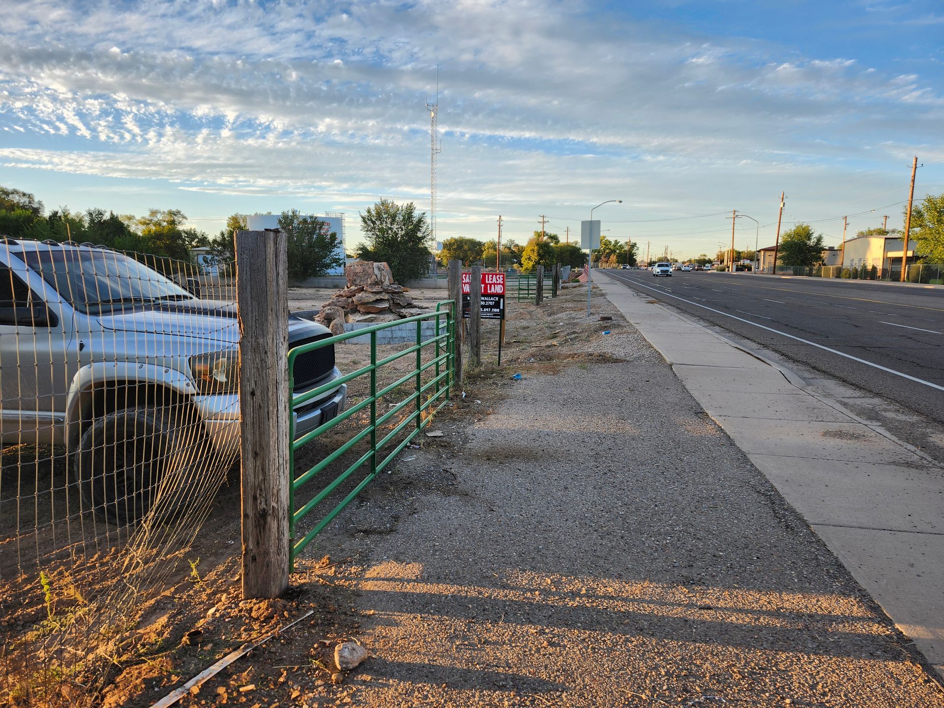 A truck is parked on the side of the road next to a fence.