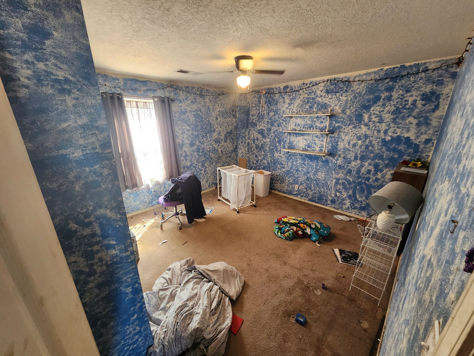 A room with blue walls and a ceiling fan.