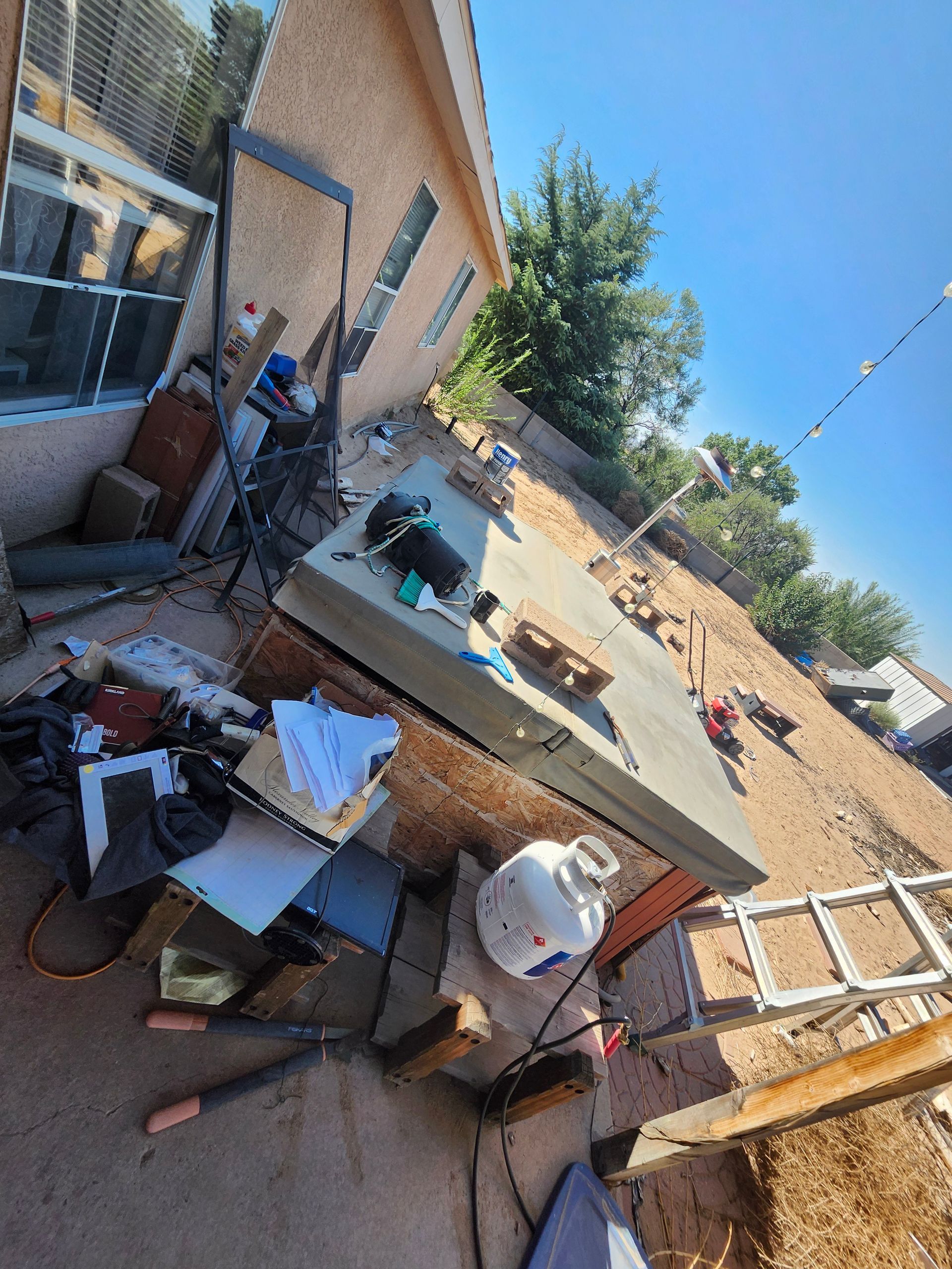 A bunch of junk is sitting on the ground in front of a house.