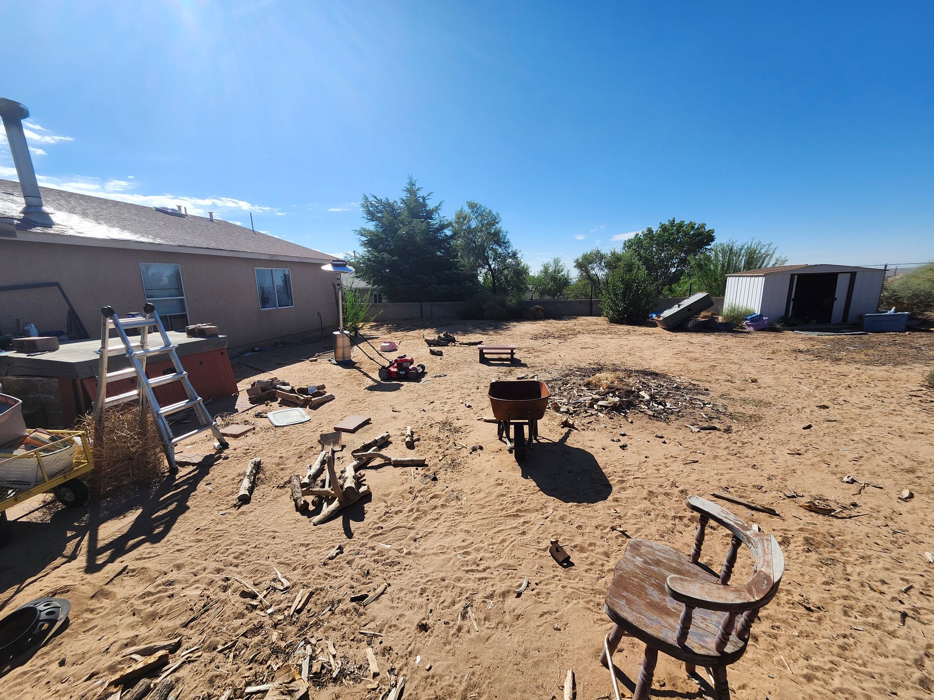 A chair is sitting in the middle of a dirt field in front of a house.