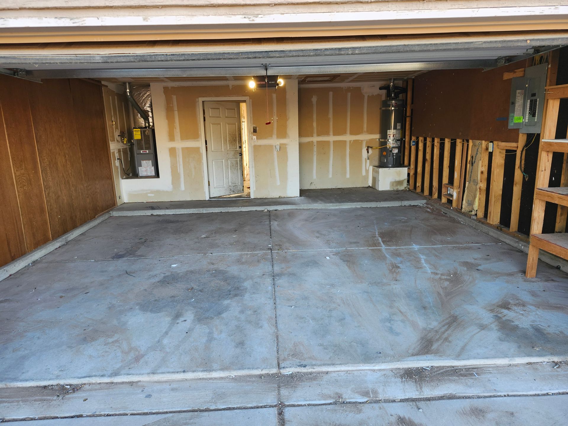 An empty garage with a concrete floor and a wooden fence