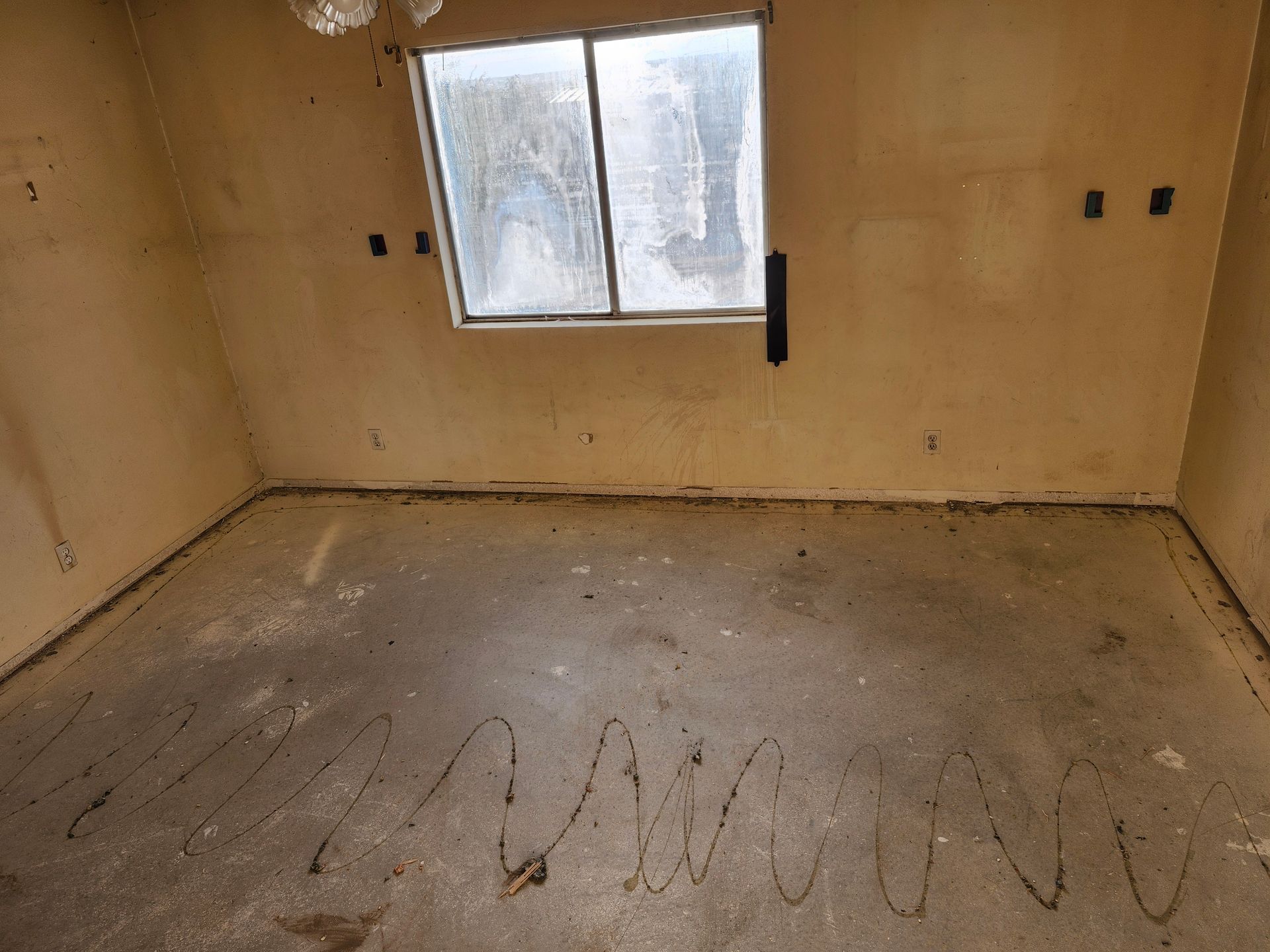 An empty room with a window and a spiral drawn on the floor.