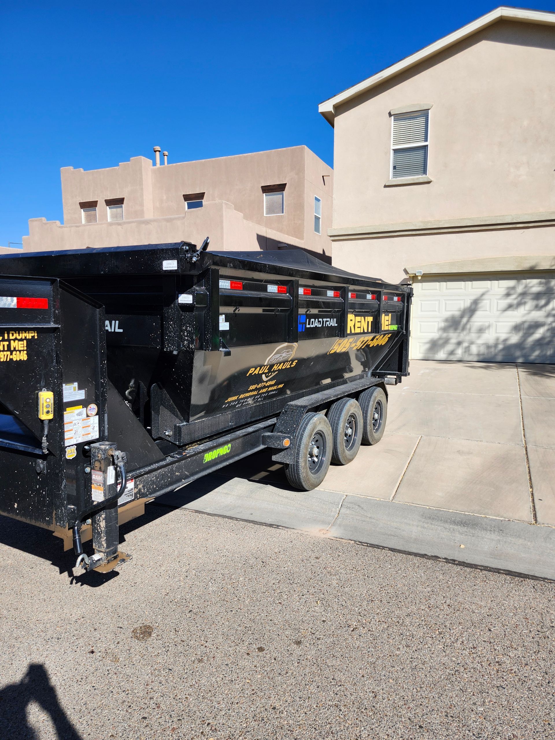 A dumpster trailer is parked in front of a house