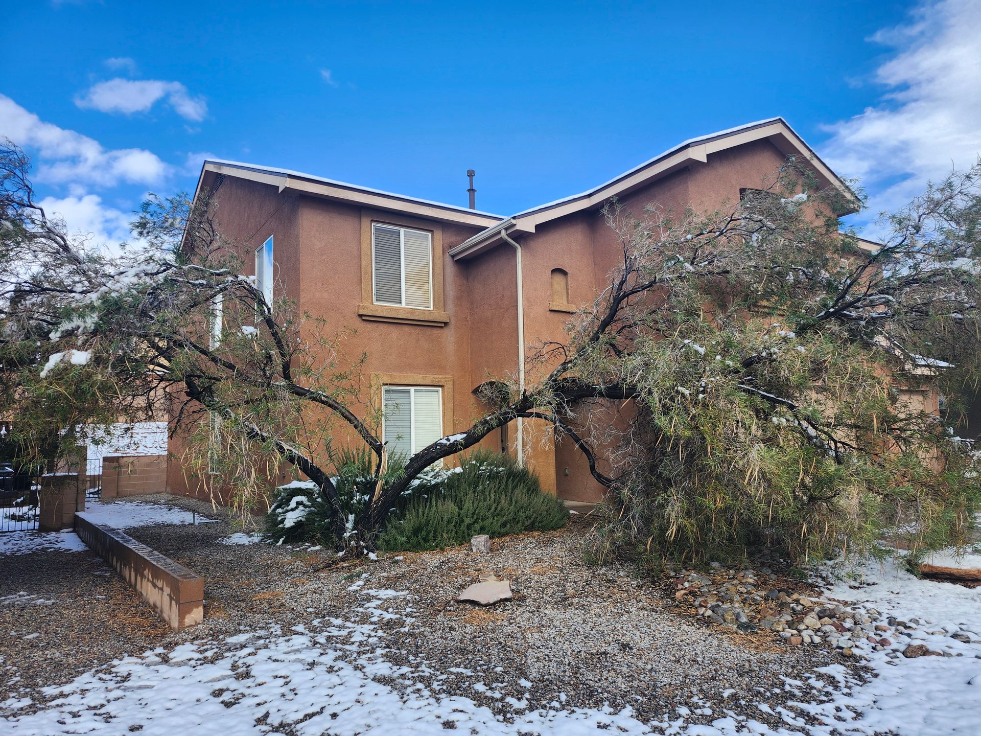 A large house with a tree in front of it covered in snow.