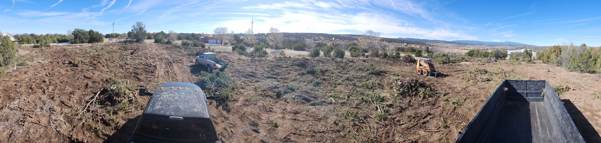 A view of a field from a wooden fence with trees in the background.
