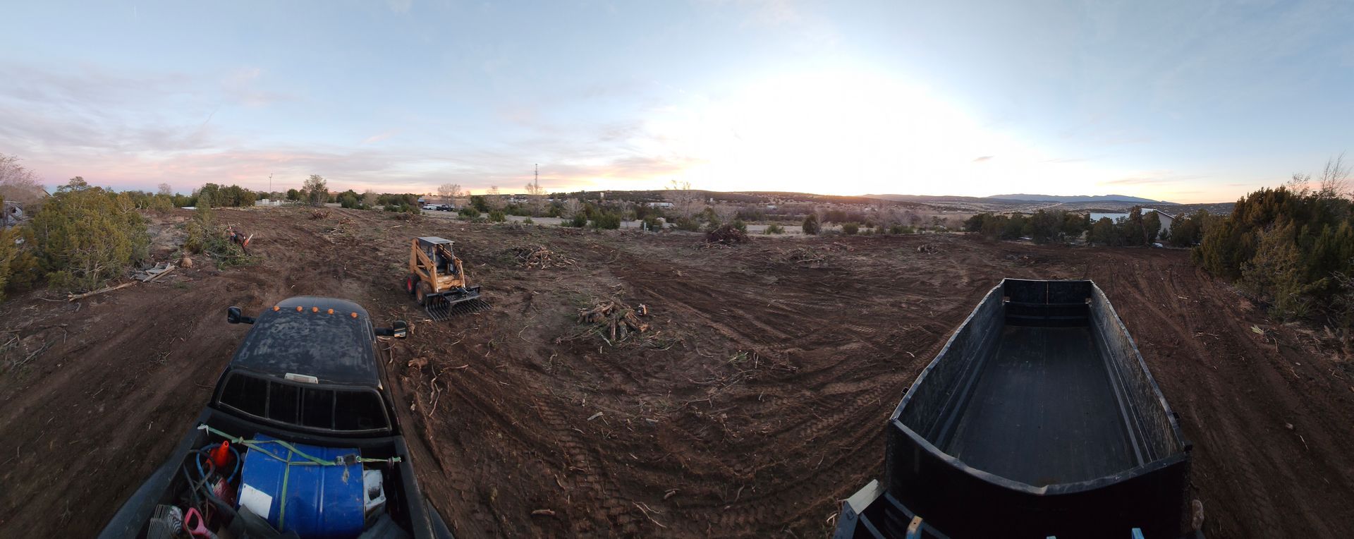 A truck and a jeep are driving down a dirt road.