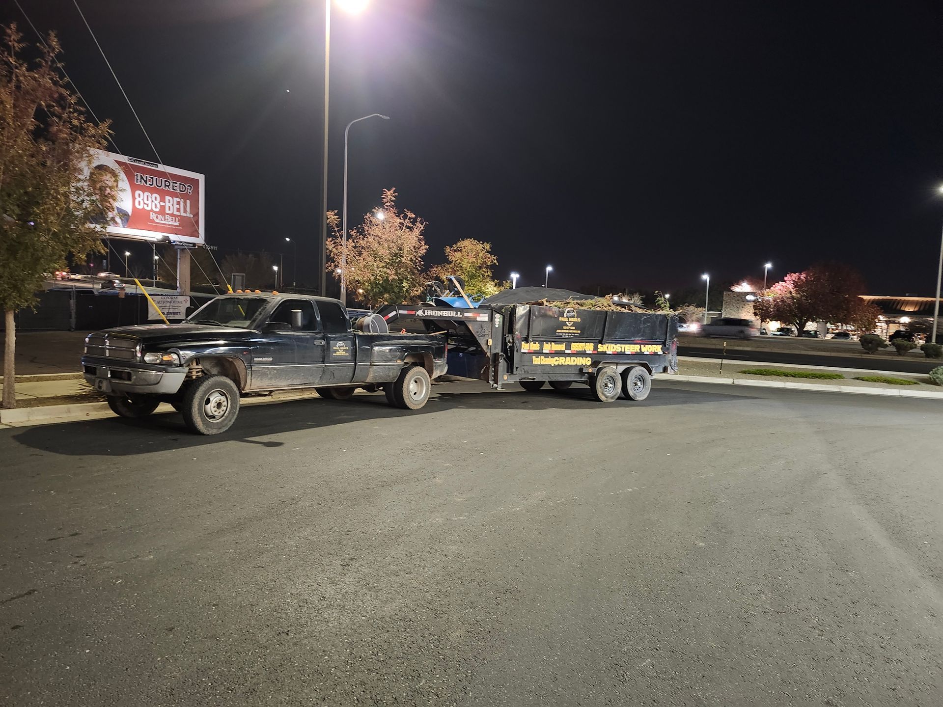 Two trucks are parked next to each other in a parking lot at night