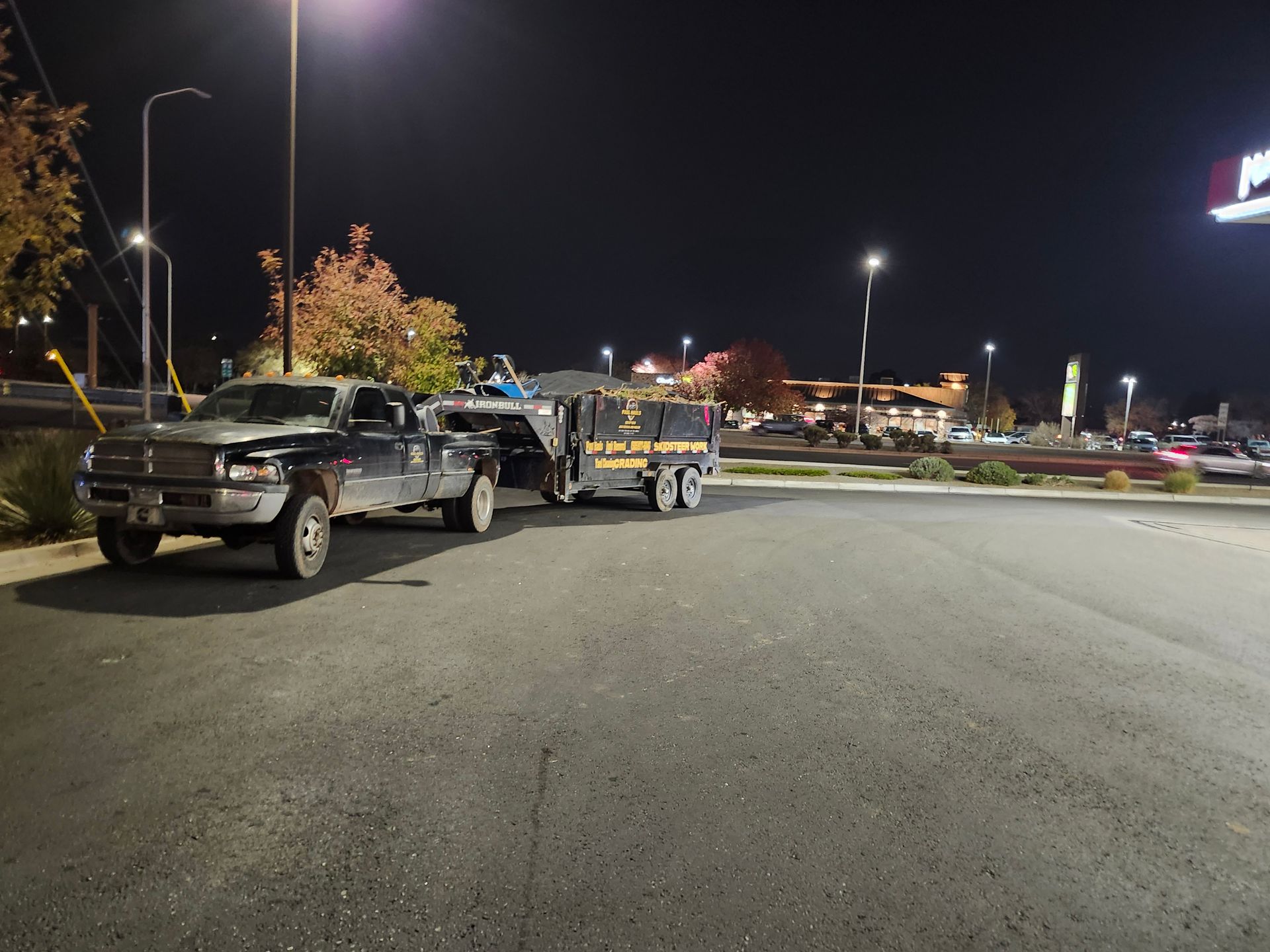 Two trucks are parked in a parking lot at night.