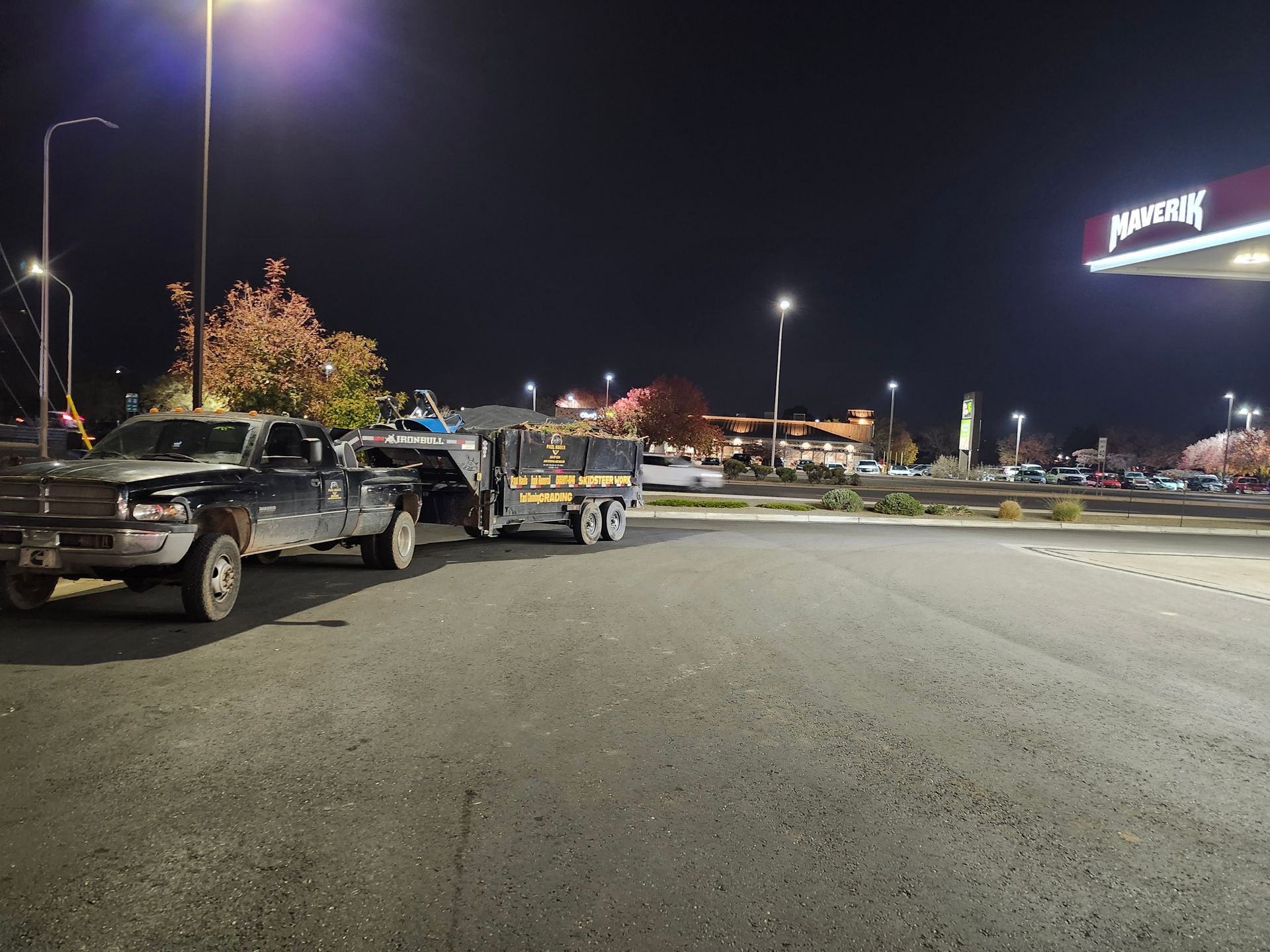 Two trucks are parked in front of a gas station at night