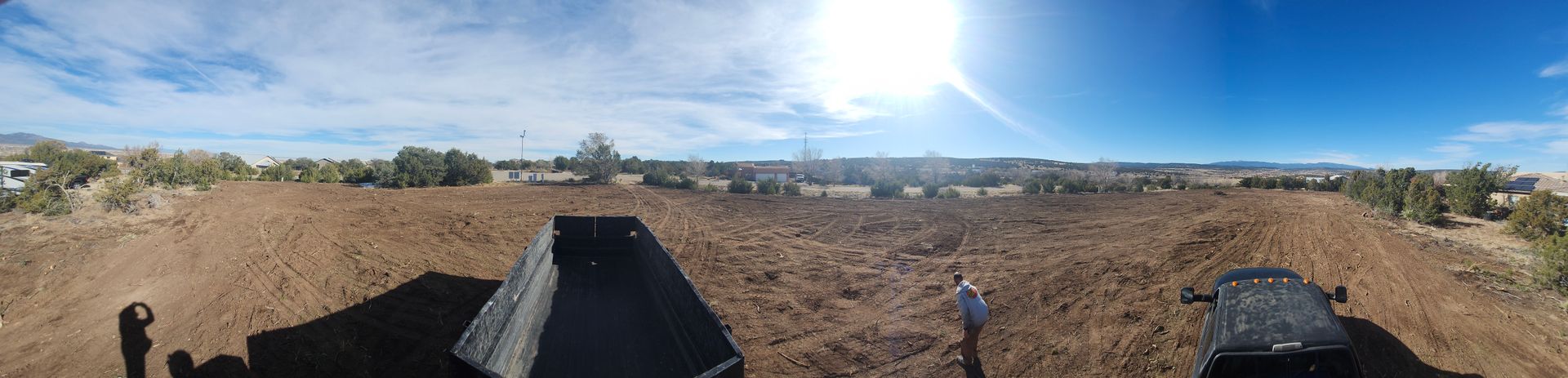 A person is riding a bike in a field with the sun shining through the clouds.