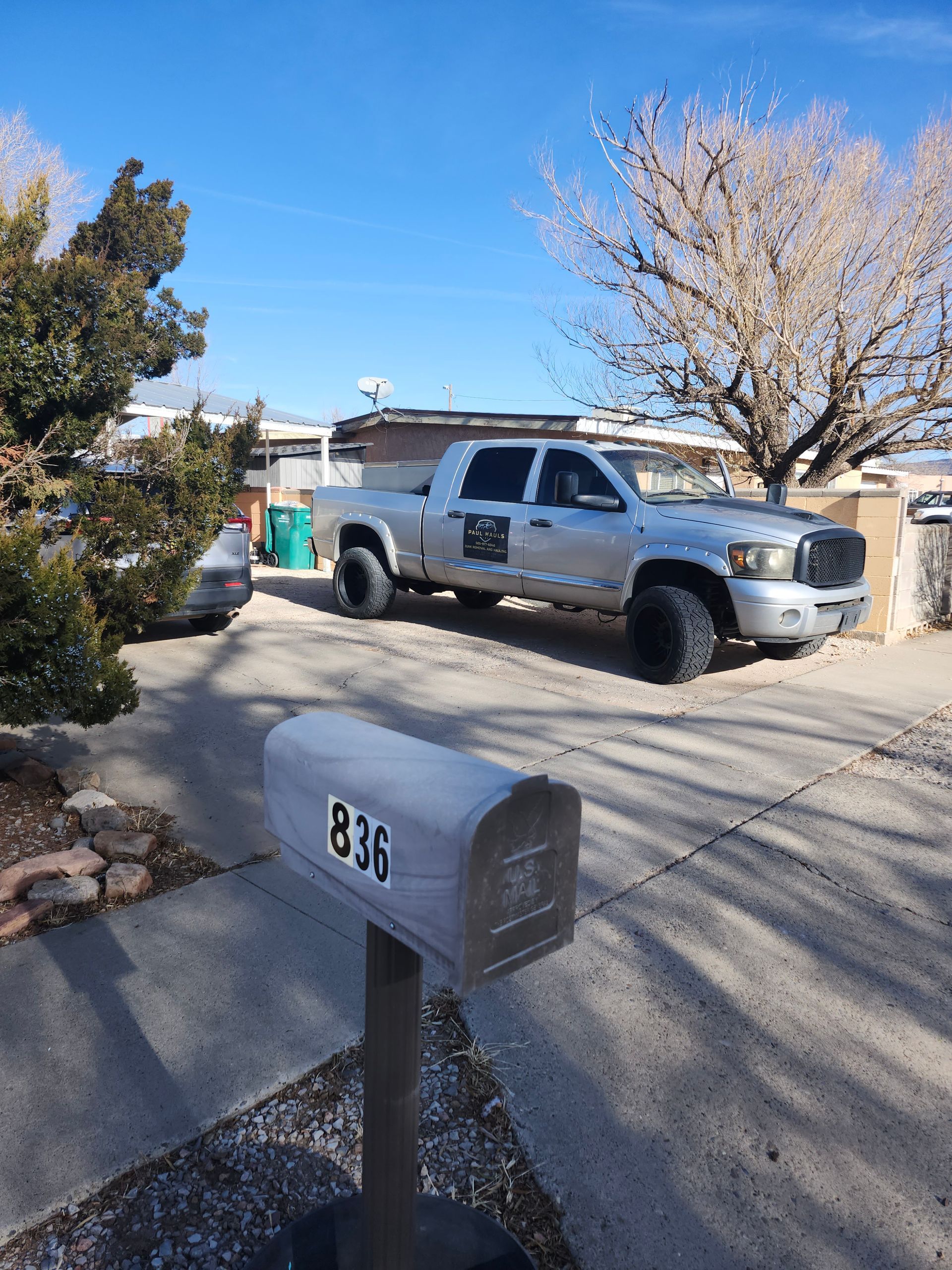 A truck is parked in front of a mailbox with the number 836 on it.