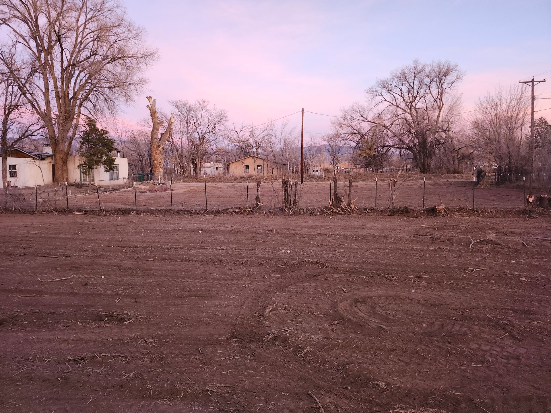 A fenced in field with a pink sky in the background
