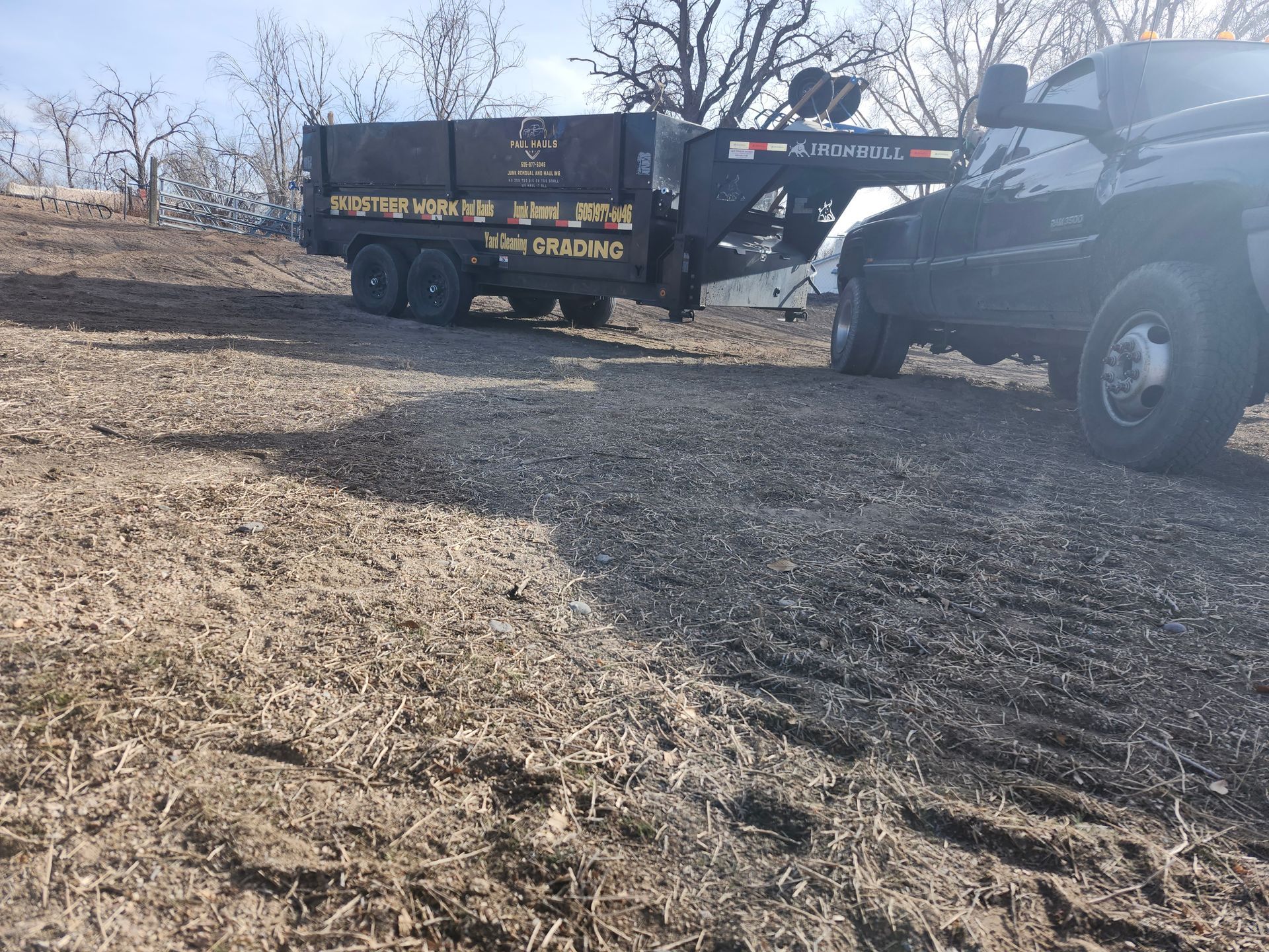 A truck with a trailer attached to it is parked on a dirt road.