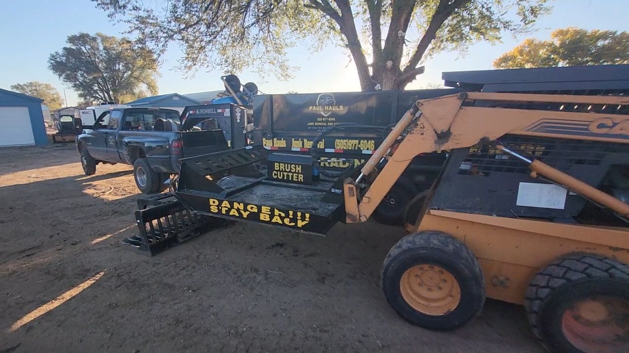A tractor with a trailer attached to it is parked in a dirt field.
