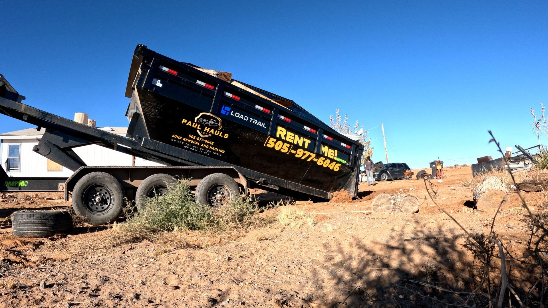 A dumpster is sitting on top of a dirt field.