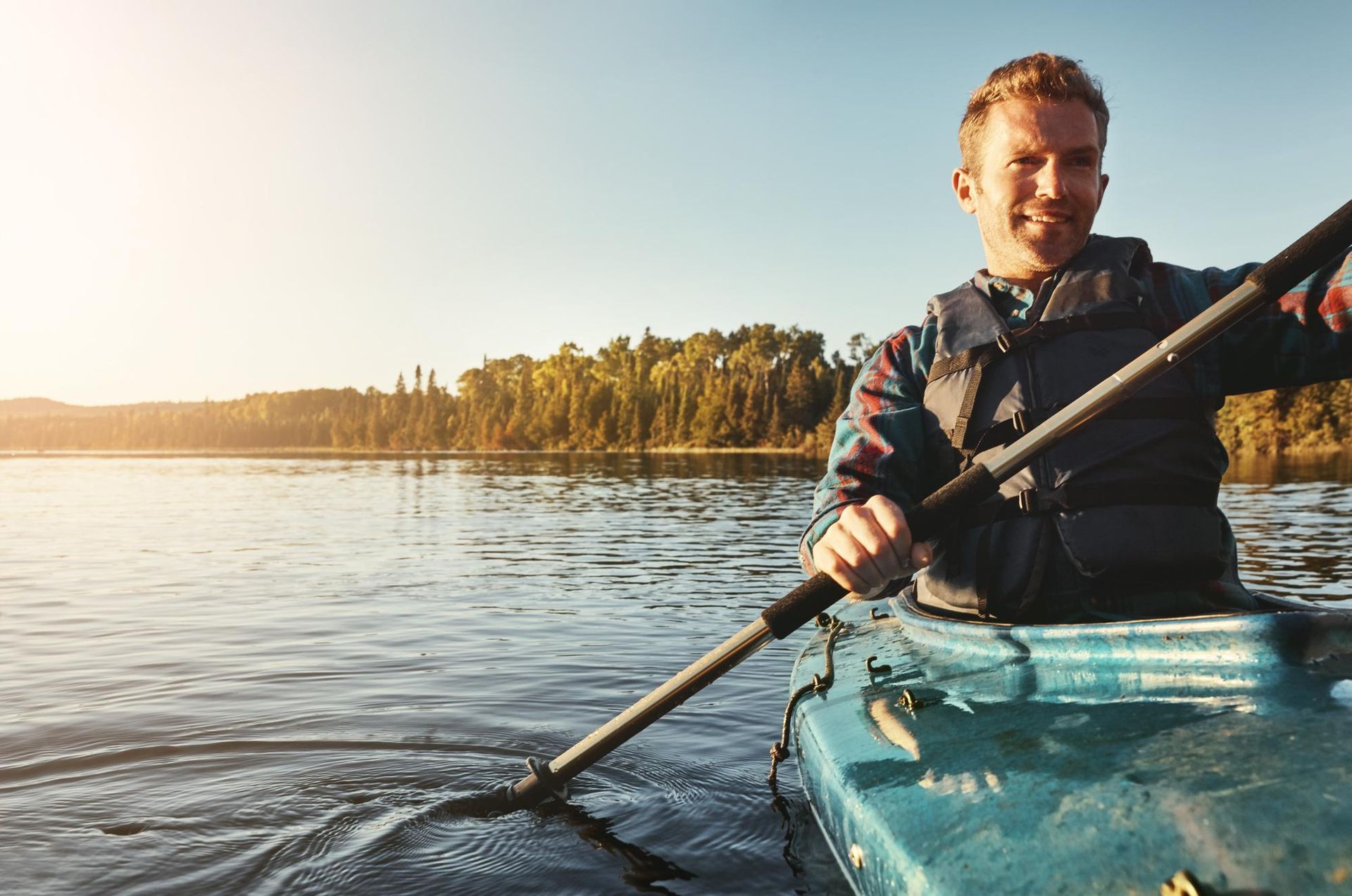 A man is paddling a kayak on a lake.