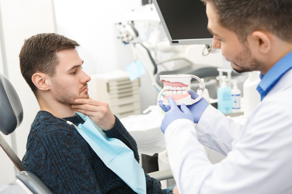 A Man is Sitting in a Dental Chair — Cairns Precision Dental Group In Woree, QLD