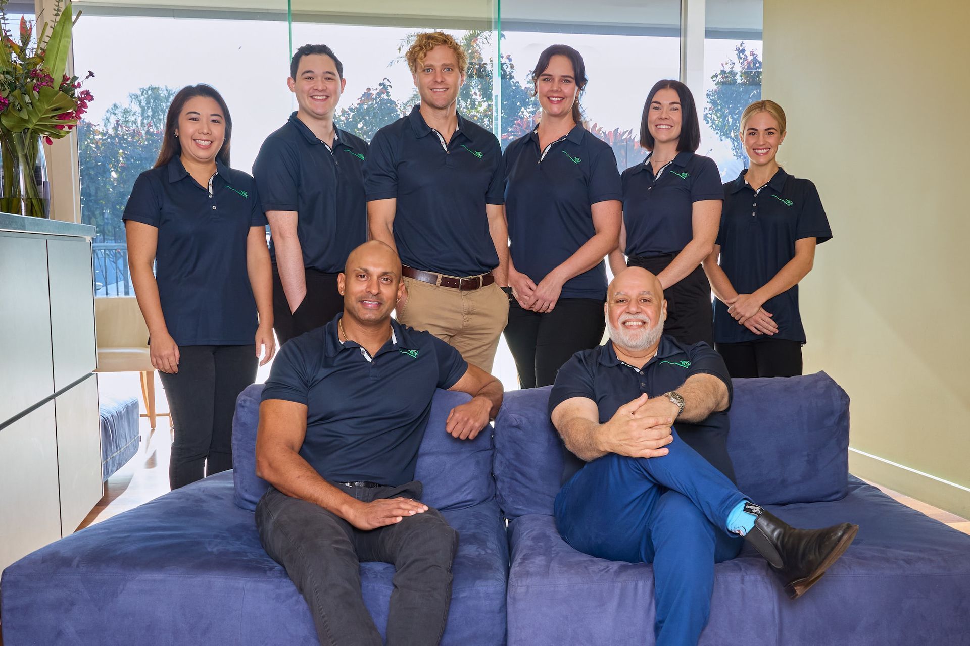 A Group of People Are Posing for a Picture While Sitting on a Couch — Cairns Precision Dental Group In Woree, QLD