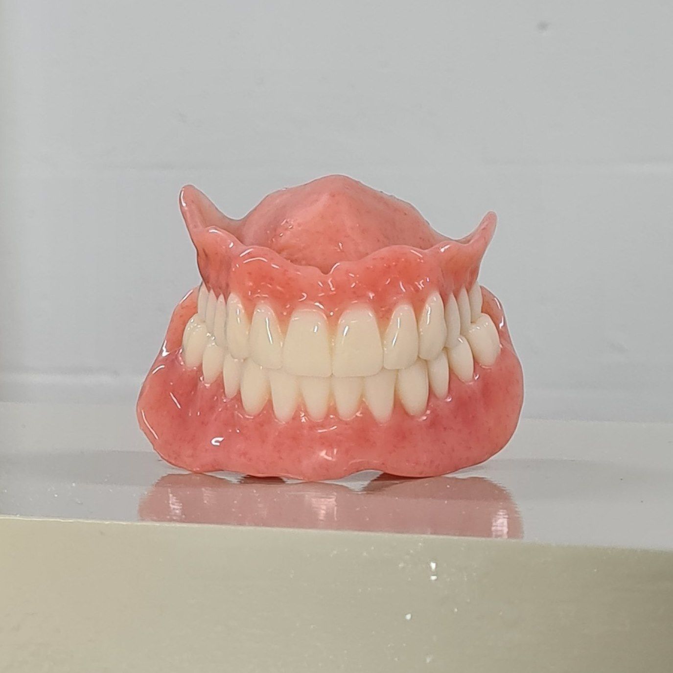 A Full Denture is Sitting on Top of a White Table — Cairns Precision Dental Group In Woree, QLD