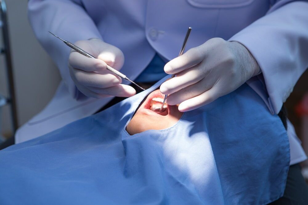 A Dentist is Examining a Patient's Teeth in a Dental Office — Cairns Precision Dental Group In Woree, QLD