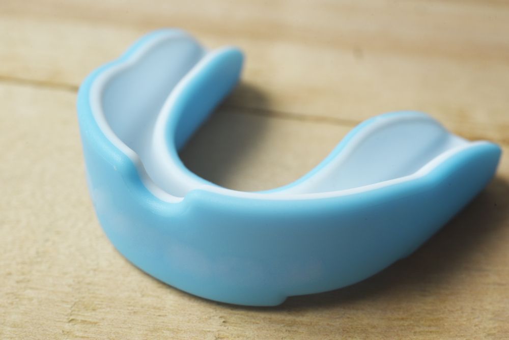 A Blue and White Mouth Guard is Sitting on a Wooden Table — Cairns Precision Dental Group In Woree, QLD