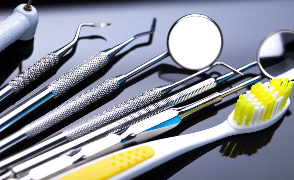 A Toothbrush and Dental Instruments on a Table — Cairns Precision Dental Group In Woree, QLD