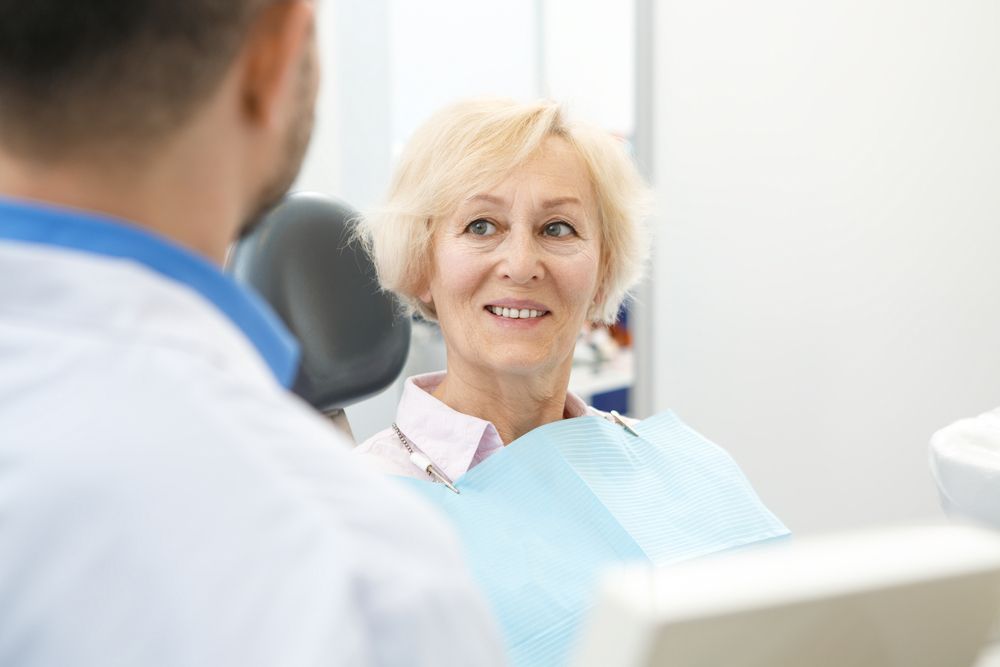 A Man and a Woman Are Sitting at a Desk Looking at a Computer Screen — Cairns Precision Dental Group In Woree, QLD